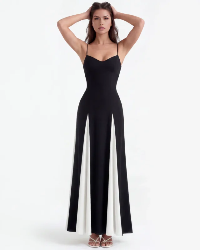 Front full-length studio portrait of the Amara black and white maxi dress, showing a subtly curved sweetheart neckline with thin spaghetti straps, a fitted black bodice, and an A-line skirt with dramatic contrasting white godet panels.