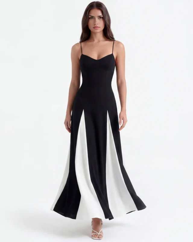 Front full-length view of the monochrome color-block maxi gown, capturing the elegant fluid flare of the black and white triangular gusset panels as the model moves against a clean white backdrop.