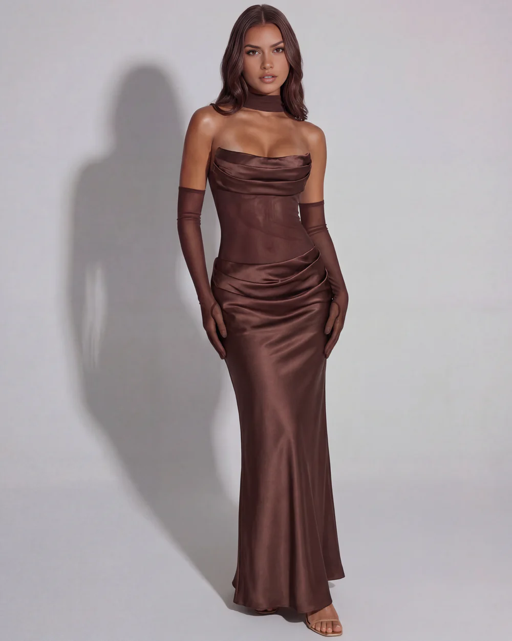 The Bianca Strapless Cowl Satin Corset Brown Maxi Gown with Operatic Mesh Gloves 01 Front full-length studio portrait of the Bianca brown maxi dress, featuring a strapless draped satin corset bodice, a sheer mesh midsection, and a matching fabric neck choker style scarf with operatic mesh gloves.