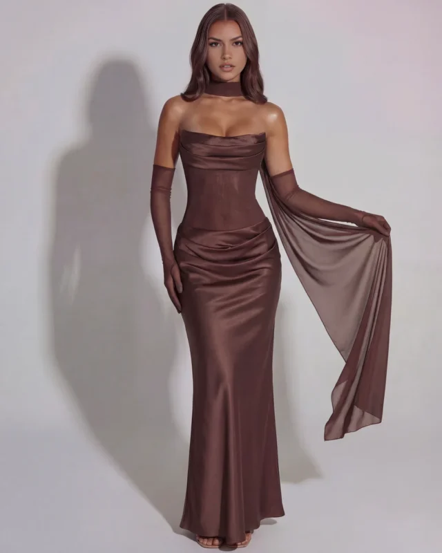 Full-length front view of the espresso brown formal corset gown, showcasing the model gracefully displaying the fluid drape of the attached sheer mesh cape scarf flowing from the shoulder.