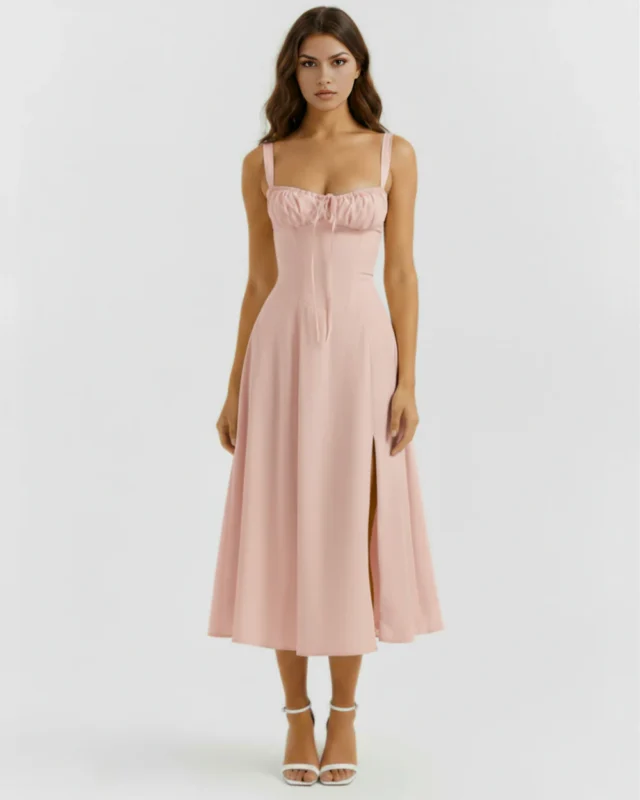 Front full-length portrait of the Capri pink midi dress, showcasing its structured corset bodice with a gathered milkmaid bust, tied neckline accents, and a flowing flared skirt with a high thigh slit.