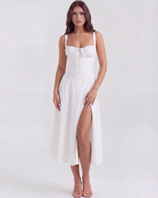 Front full-length view of the Capri white midi dress, featuring a structured milkmaid corset bodice, adjustable wide shoulder straps, and a fluid A-line skirt with a dramatic high thigh slit.