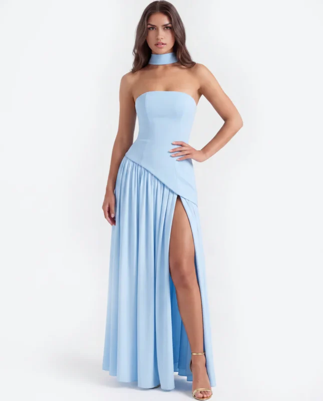 Front full-length portrait of the Caterina baby blue maxi dress, showcasing a strapless corset bodice with an asymmetrical dropped-waist seam, a matching fabric neck choker, and a gathered floor-length skirt with a high thigh slit.