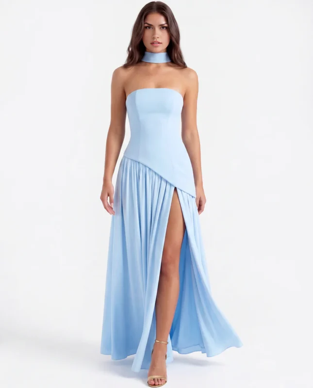 Front full-length view of the light blue strapless corset maxi gown, highlighting the fluid movement of the gathered georgette skirt, a bold leg slit, and gold strappy high heels.