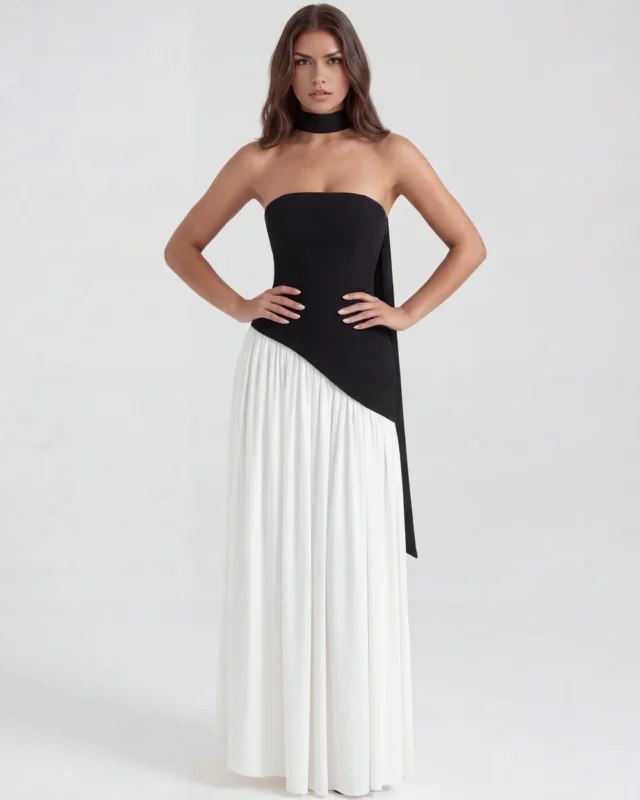 Front full-length studio shot of the Caterina black and white maxi gown, featuring a structured black strapless corset bodice, an asymmetrical drop waistline, a matching black choker, and a flowing white gathered skirt.