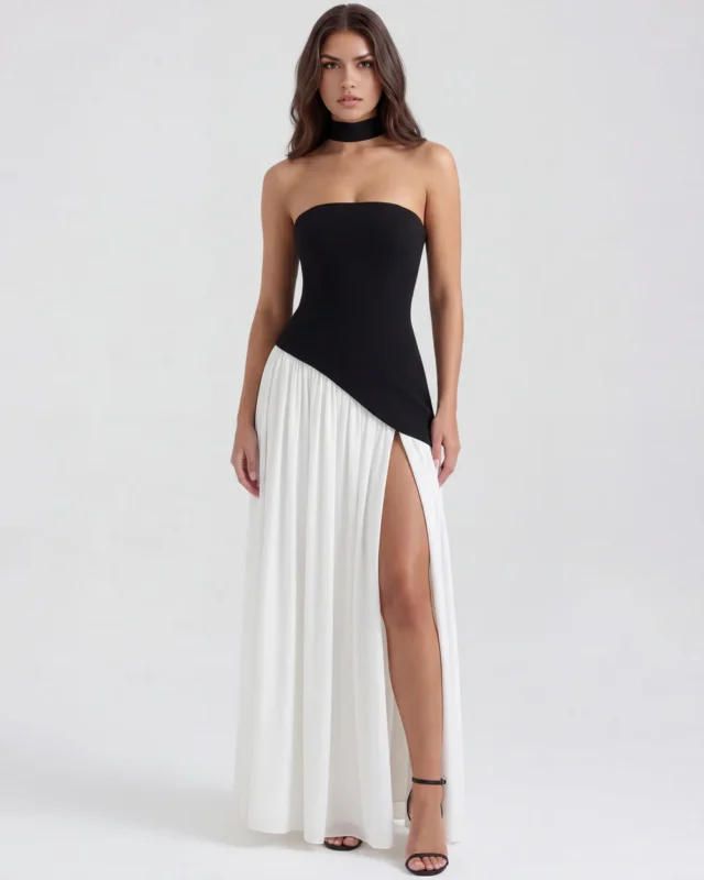 Balanced front portrait of the monochrome black and white corset evening dress, displaying the sharp diagonal waist seam line and a dramatic high thigh slit in the white skirt paired with black heels.