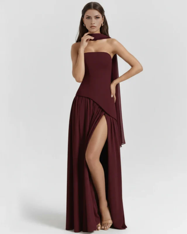 Front full-length view of the rich wine burgundy strapless corset maxi gown, highlighting the fluid drape of the gathered georgette skirt, a daring high thigh slit, and a matching neck scarf.
