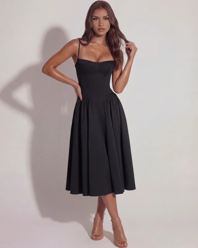 Front full-length view of The Delphine Bustier Midi Dress in timeless black, showcasing the romantic structured underwired corset bodice, minimal spaghetti straps, and gathered pleat flare skirt.