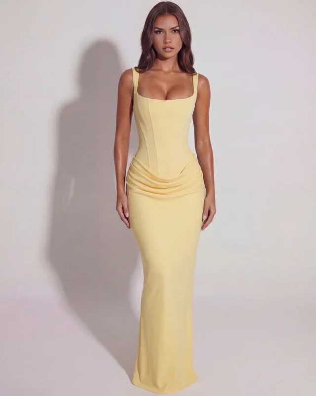 Front full-length shot of a light butter yellow satin corset gown, displaying the supportive wide shoulder straps, defined vertical torso seams, and long sweeping column skirt.