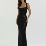 Front full-length studio portrait of the Genevieve black maxi gown, showcasing a tailored square neckline, thick supportive shoulder straps, and a body-contouring column silhouette entirely encrusted with shimmering crystals.