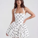Front mid-length view of The Giuliana Polka Dot Halter Puffball Mini Dress in black and white, highlighting the structured square halter neckline, princess-seamed bodice, and voluminous puffball skirt.