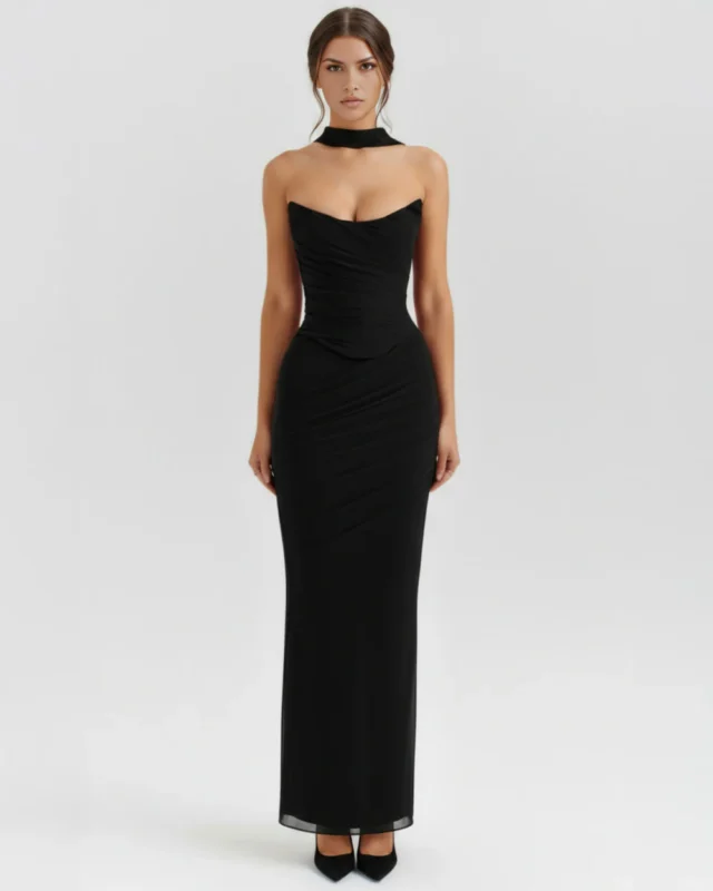 Front full-length portrait of the Victoria black maxi dress, featuring a strapless sweetheart-style curved bust-line, a gathered mesh draped bodice, a matching black neck scarf, and a column skirt.