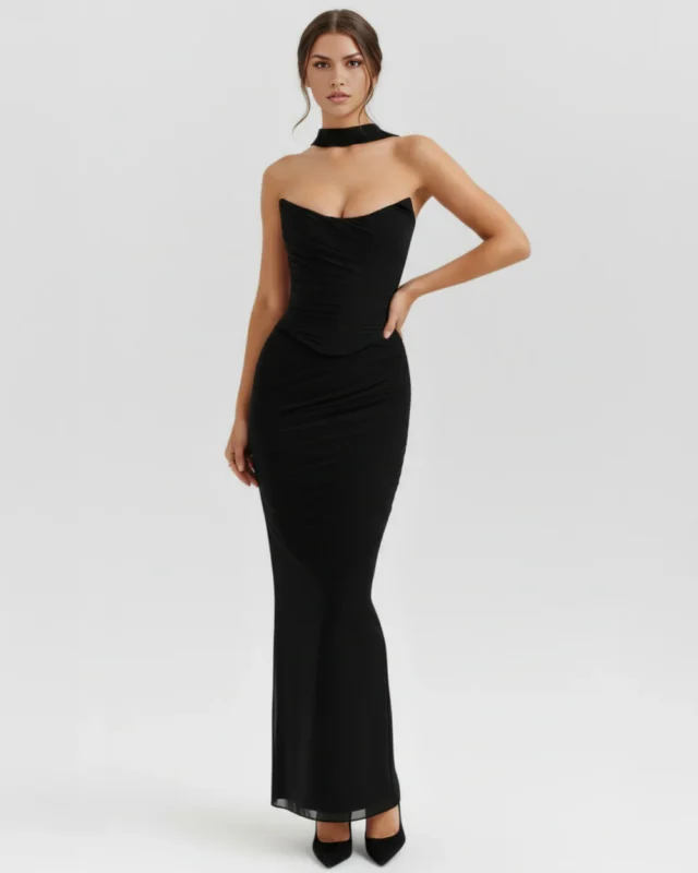Full-length studio shot of the black strapless mesh evening gown with a hand-on-hip pose, highlighting the curve-contouring fit and formal styling with black stiletto heels.