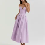 Front full-length view of a model in the Mirabella violet midi dress, showcasing the structured strapless corset bodice, plunging sweetheart neckline, and voluminous pleated midi skirt paired with white ankle-strap heels.