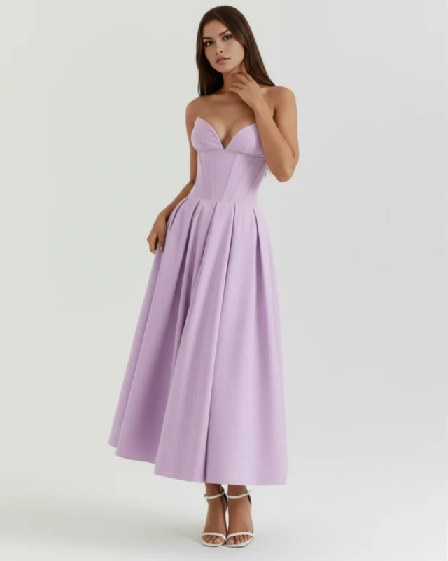 Front full-length view of a model in the Mirabella violet midi dress, showcasing the structured strapless corset bodice, plunging sweetheart neckline, and voluminous pleated midi skirt paired with white ankle-strap heels.