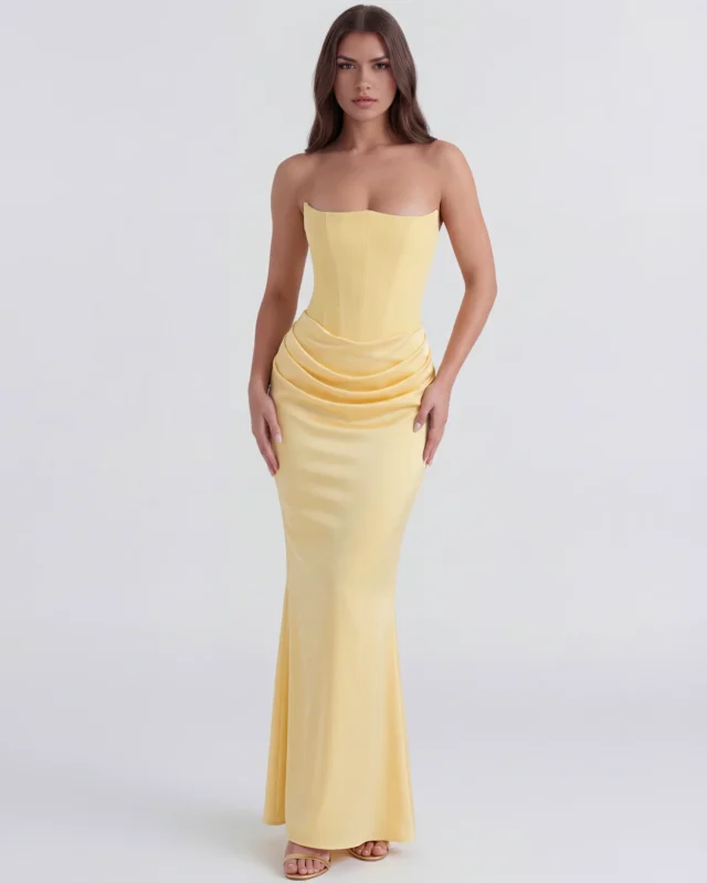 Front full-length view of the Rosalinda strapless corset maxi gown in pastel butter yellow, showcasing the structured pointed bustline, fitted drop waist, and elegant cowl draping over the lower hips.