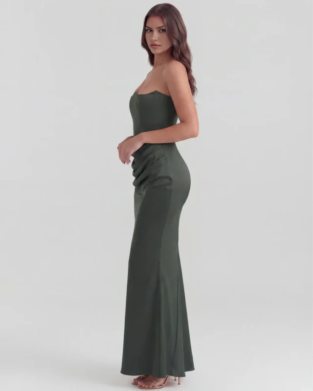 Side profile full-length view of a premium dark green strapless satin dress, highlighting the fluid, figure-skimming silhouette and sophisticated evening wear style.