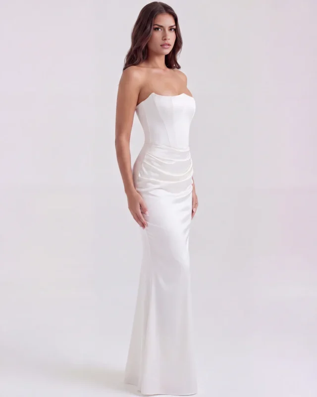 Three-quarter front full-length perspective of a white strapless bridal engagement gown, showcasing the elegant drop-waist draping and a striking red-carpet silhouette.