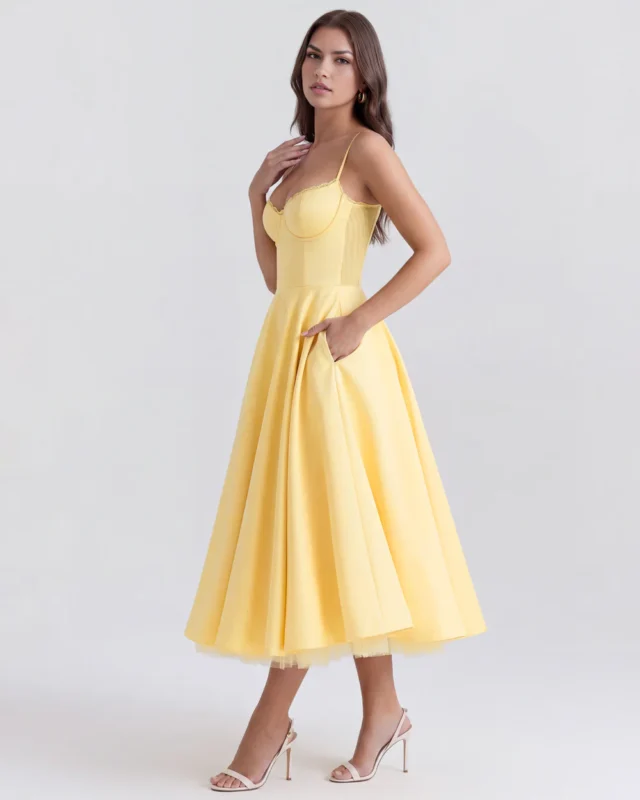 Side profile perspective of the pastel yellow corseted midi dress with a hand in the functional side pocket, highlighting the structured waistline and elegant flare of the satin-feel skirt.