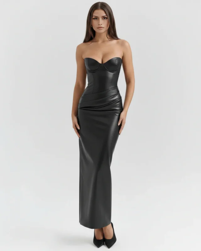 Front full-length studio shot of the black faux leather strapless evening dress with the model's arms resting at her sides, highlighting the premium matte finish, smooth corsetry paneling, and pointed black stiletto heels.